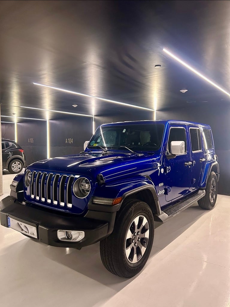 Blue Jeep Wrangler SUV displayed in a modern showroom with bright overhead lighting
